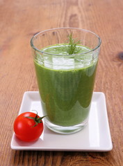 Green spinach smoothie with small red tomato