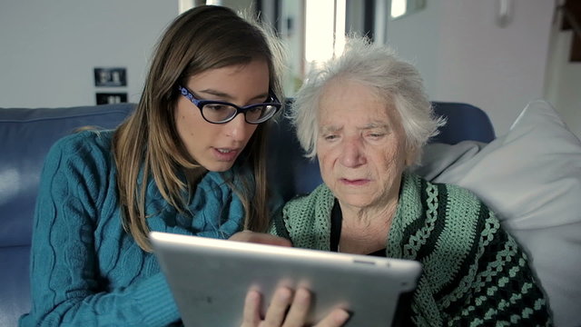 Granddaughter Teaching Grandmother How to Use a Tablet PC
