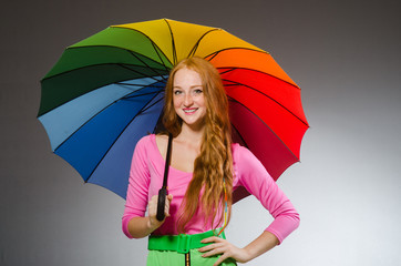 Woman holding colourful umbrella in studio