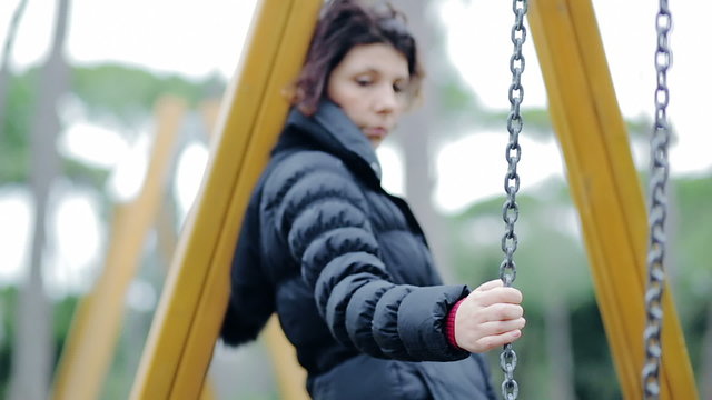 Depressed girl on a swing in the autumn park