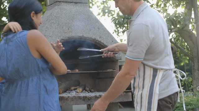MS Man working at BBQ with his wife and son