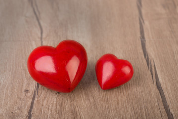 Two red stone hearts on wooden surface