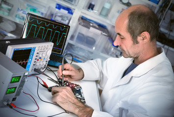 Senor male tech fixes motherboard in computer repair shop