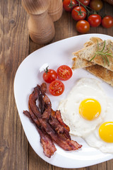 Fried egg and bacon on a plate with spices and vegetables