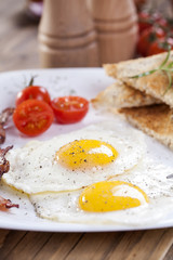 Fototapeta na wymiar Fried egg and bacon on a plate with spices and vegetables