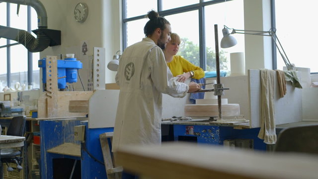 Male potter teaching pottery to woman