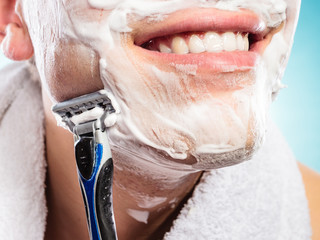 Handsome man shaving with razor