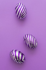 easter eggs with stripes, on a plain purple background