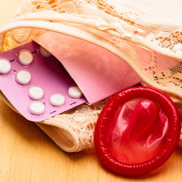 Oral contraceptive pills and condom on lace lingerie
