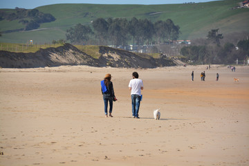 pareja joven caminando por la playa de oyambre en invierno