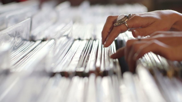 CU A Young Woman's fingers flick through a rack of vintage records  