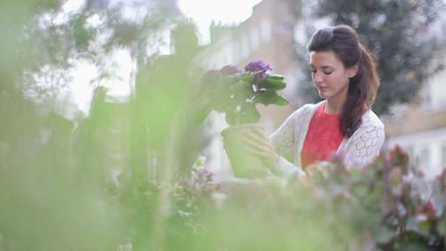 Young woman browses an array of flowers outside a Florist and picks up to inspect 