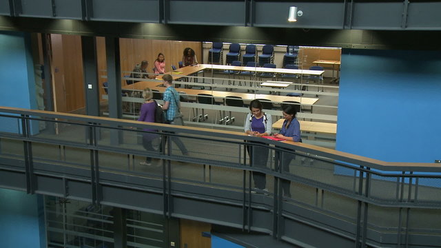 Two Female Students Texting Out Of Classroom