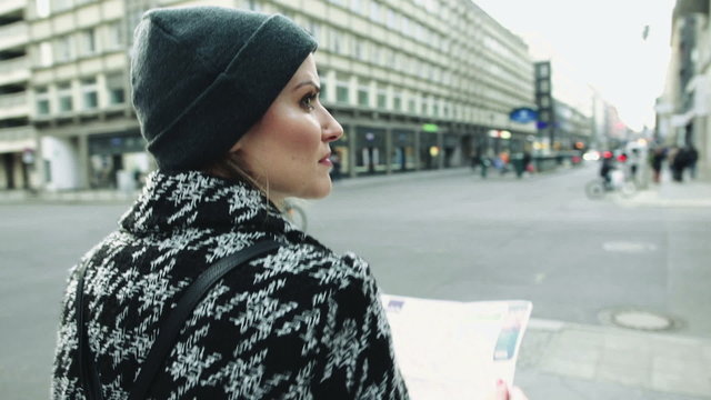 Young beautiful woman travelling with a map in the city.