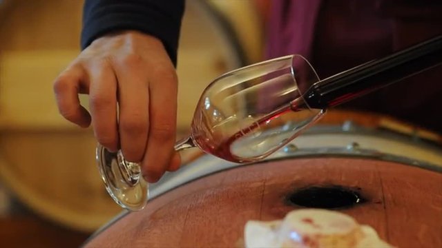 Winemaker in cellar making wine test.