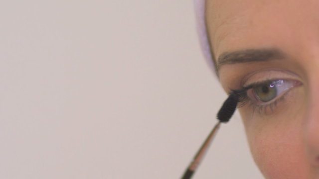 BCU PAN OF A WOMAN APPLYING MASCARA