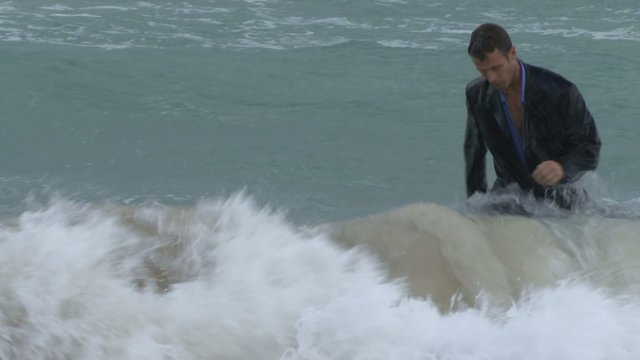 Male walking out of the ocean in suit