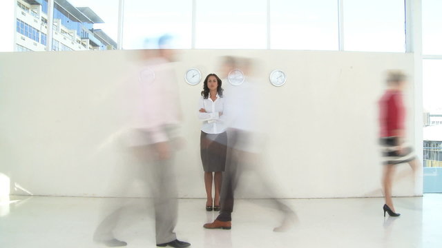 WS PAN OF A BUSINESSWOMAN STANDING STILL WITH BLURRED PEOPLE WALKING PAST