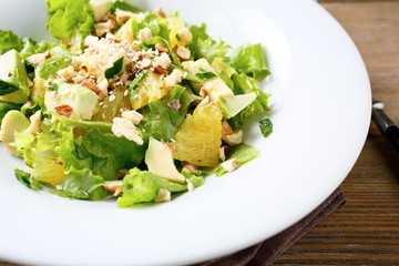 Fresh salad with avocado, lettuce, orange and crushed nuts