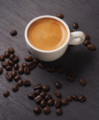 Cup of hot espresso coffee and coffee crop on wood board