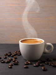 Cup of hot espresso coffee and coffee crop on wood board
