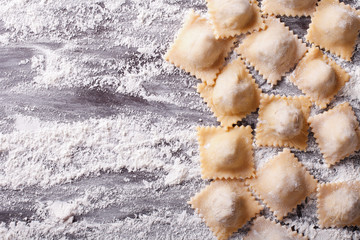 raw ravioli with flour on the table. horizontal top view