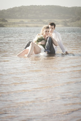 Fototapeta premium Young beautiful couple sitting in water flirting in love