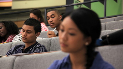 CU of female and students taking notes in lecture theatre - Powered by Adobe