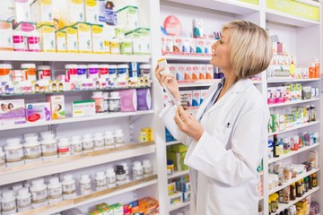 Smiling pharmacist holding prescription and medicine