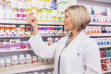 Smiling pharmacist looking at medicine