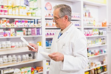 Senior pharmacist looking at medicine and prescription