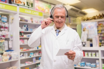 Senior pharmacist with headphone reading prescription