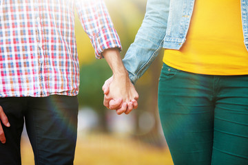 Loving couple holding hands outdoors on sunny nature background