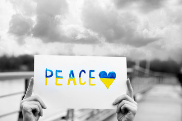 Hands holding paper with Peace of Ukraine