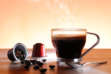Capsules and cup of hot espresso coffee
