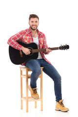 Obraz premium The guitarist posing on a chair