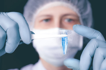 Scientist or tech holds liquid biological sample in gloved hands