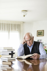 Senior man reading book relaxed at home