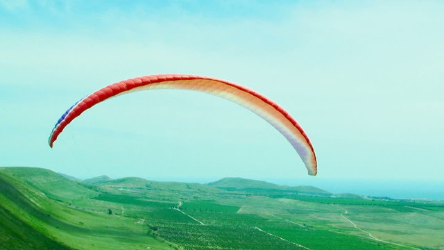 Paraglider Soaring Over Green Hill