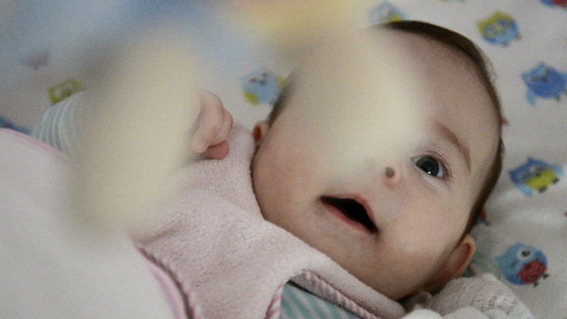 Baby looking at toy above its head and babbling