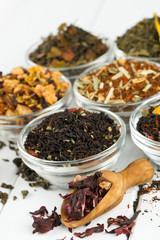 assortment of dry tea in glass bowls on wooden surface