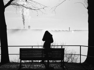 depressive Frau im Nebel allein vor der Parkbank stehend