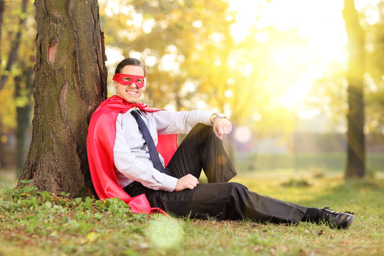Man in superhero outfit sitting in a park