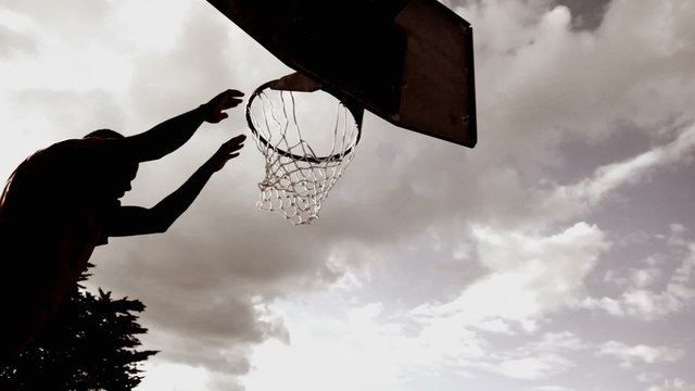 Male basketballer dribbling and dunking