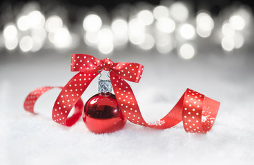 Red bauble with matching ribbon on snow