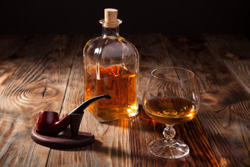 Bottle of brandy and a glass smoking pipe