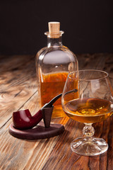 Bottle of brandy and a glass smoking pipe