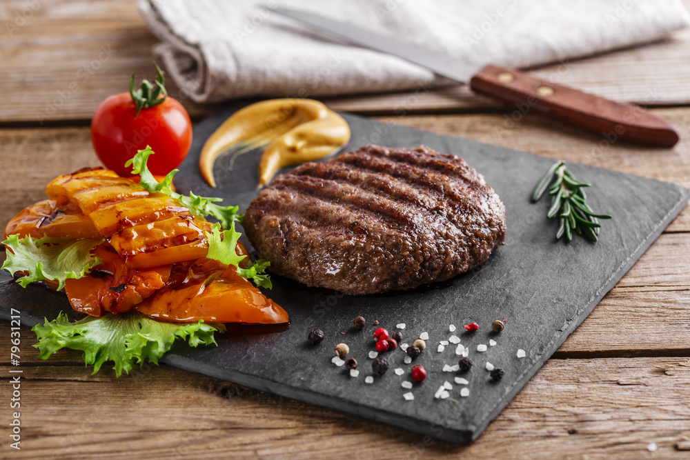 Wall mural burger grill with vegetables and sauce on a wooden surface