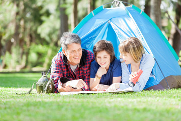 Family Studying Map While Lying In Tent