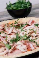 Italian pizza with ham, mushrooms,bacon and rucola ready to bake